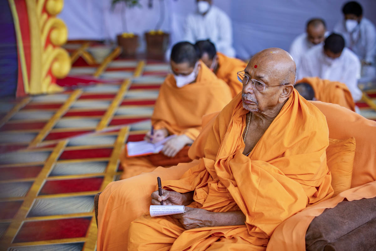 Pujya Tyagvallabh Swami writes notes during the assembly