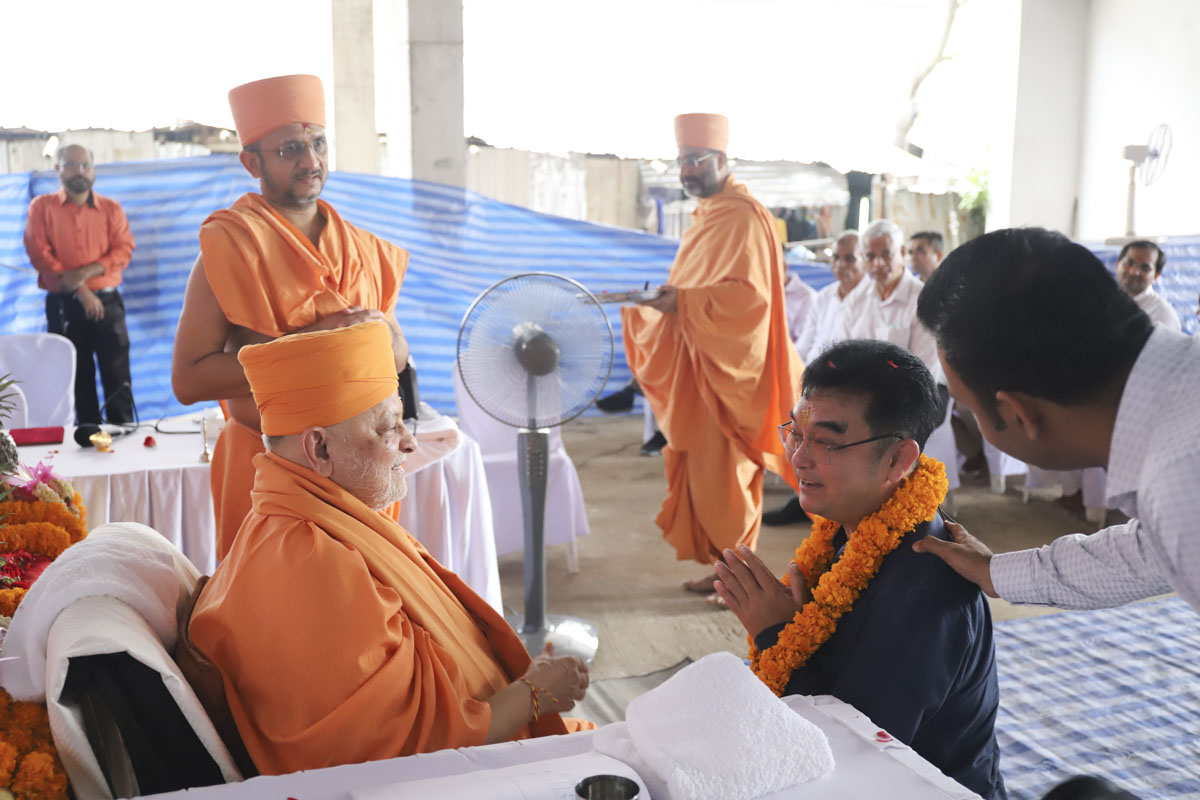 Pujya Ishwarcharan Swami honors a well-wisher with a garland