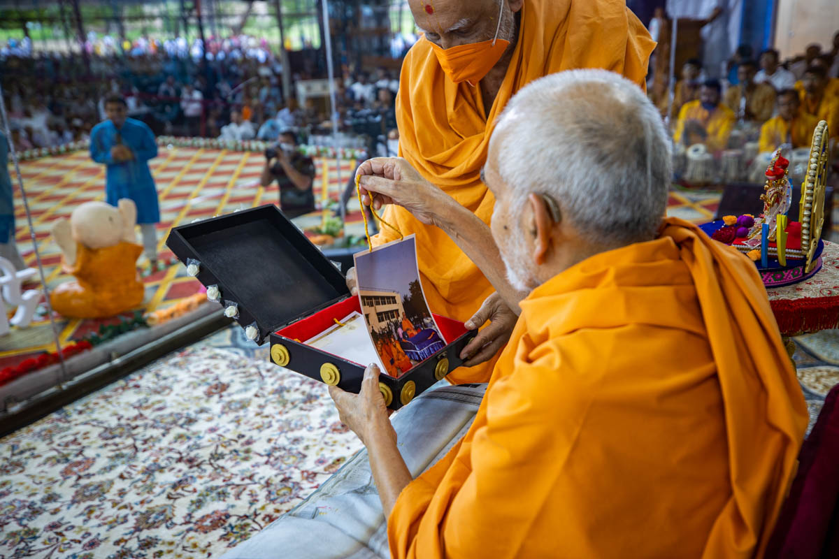 Swamishri sanctifies an invitation card for the evening satsang assembly