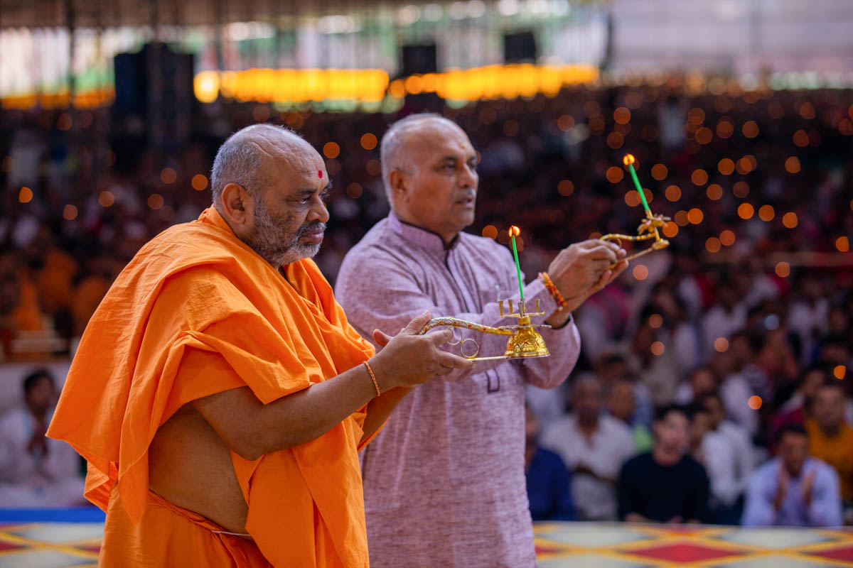 Bhagwatcharan Swami and a devotee perform the arti
