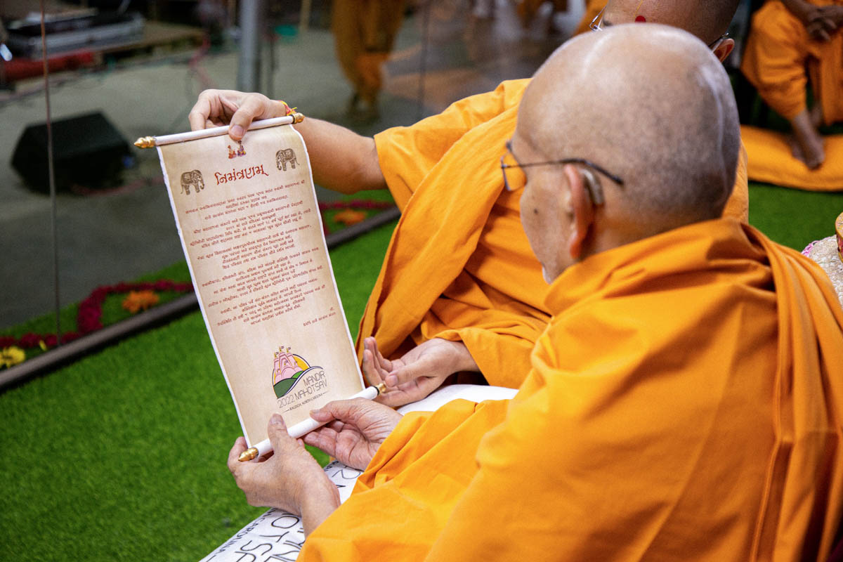 Swamishri reads an invitation to the Raleigh Mandir Mahotsav