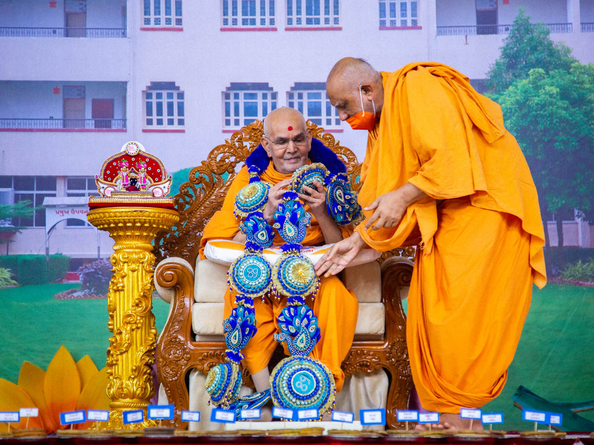 Atmaswarup Swami honors Swamishri with a garland