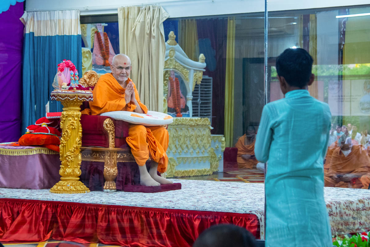 Swamishri greets a child with folded hands