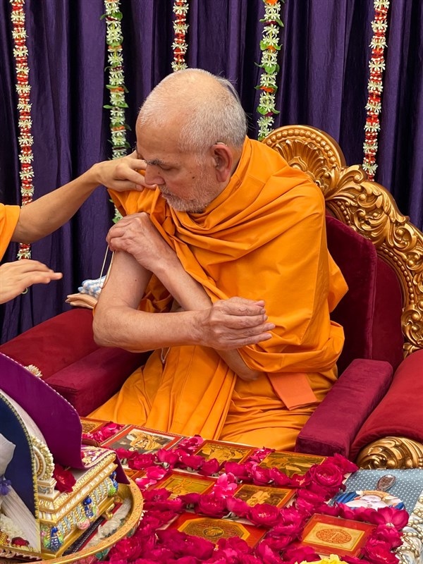 Swamishri applies a tilak on his upper arm