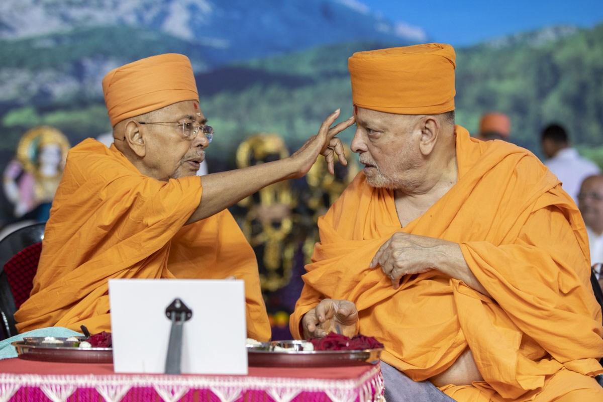 Pujya Tyagvallabh Swami applies a chandlo to Pujya Ishwarcharan Swami