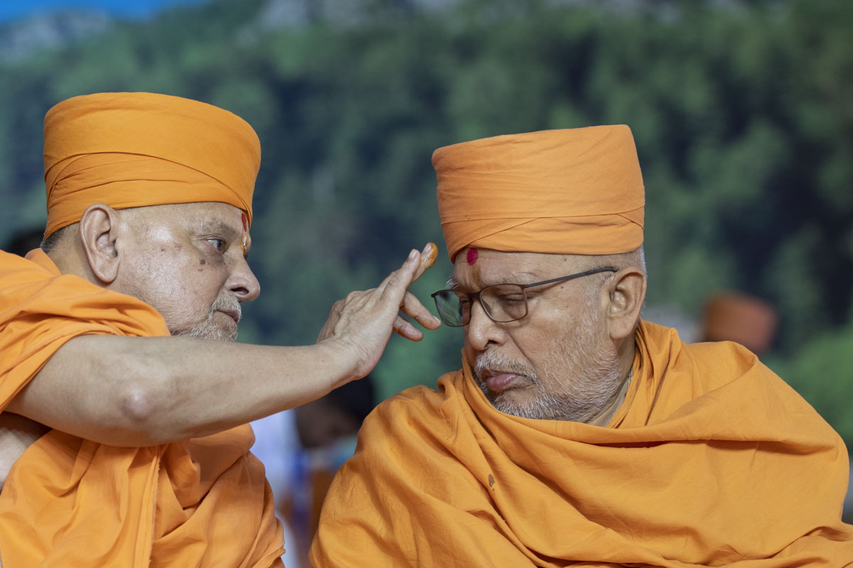 Pujya Ishwarcharan Swami applies a chandlo to Pujya Ghanshyamcharan Swami
