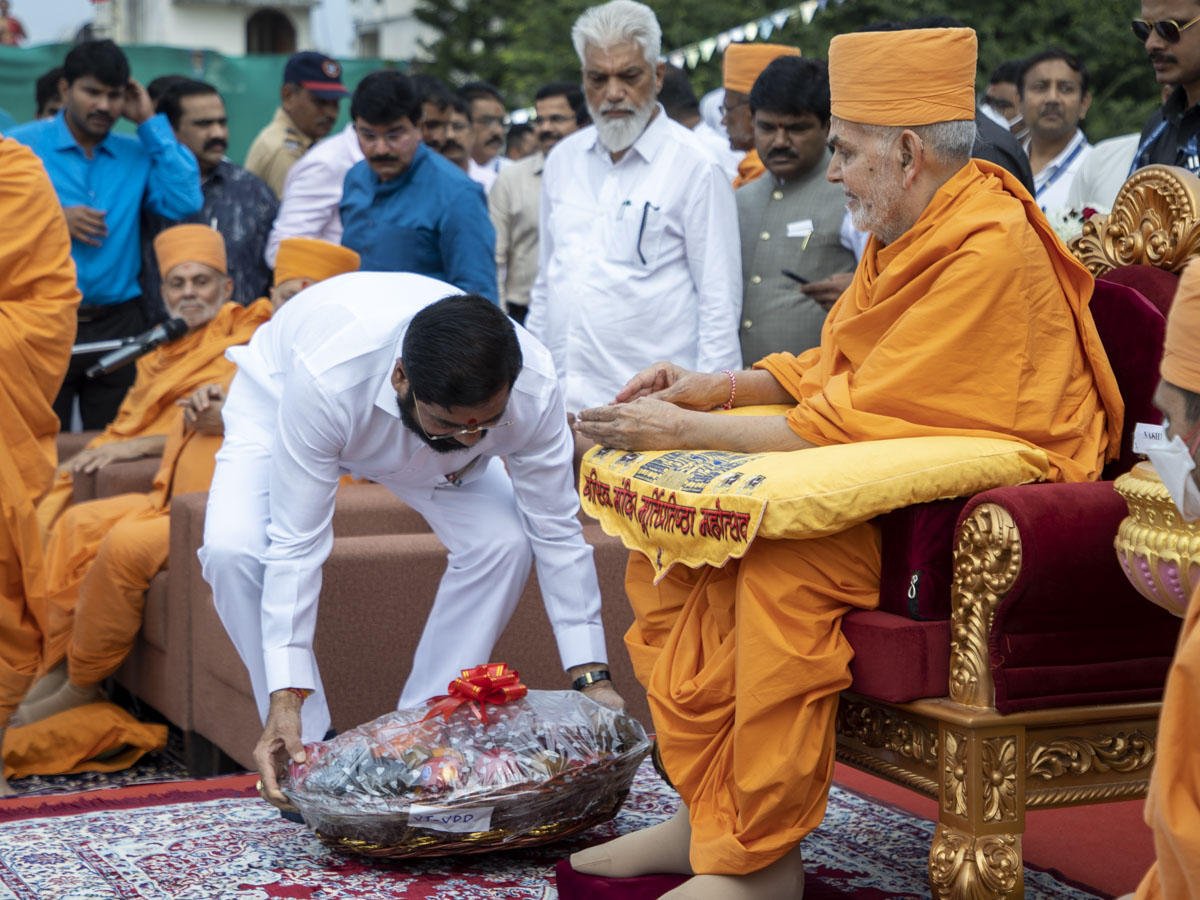 Shri Eknath Shinde offers a basket of fruits to Swamishri