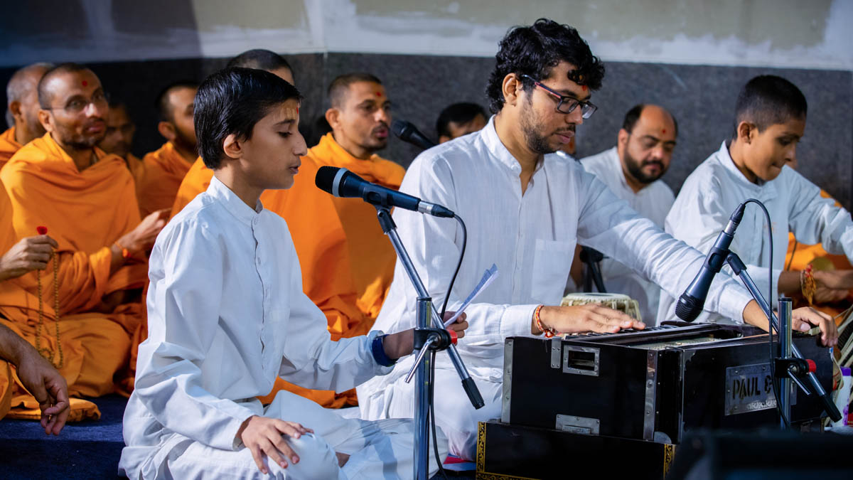 A child sings a kirtan in Swamishri's daily puja