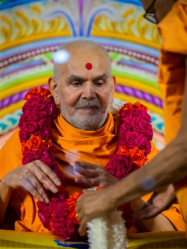 Pujya Bhaktipriya Swami (Kothari Swami) honors Swamishri with a garland