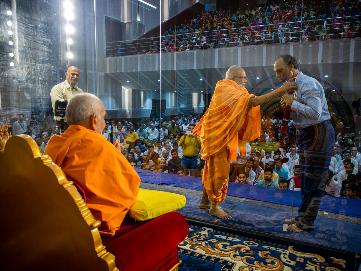 Pujya Kothari Swami honors a well-wisher with a garland