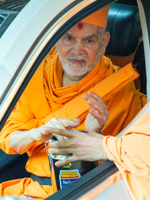 Swamishri touches the sacred water of the well