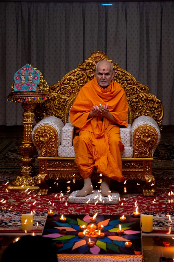Swamishri holds a lamp