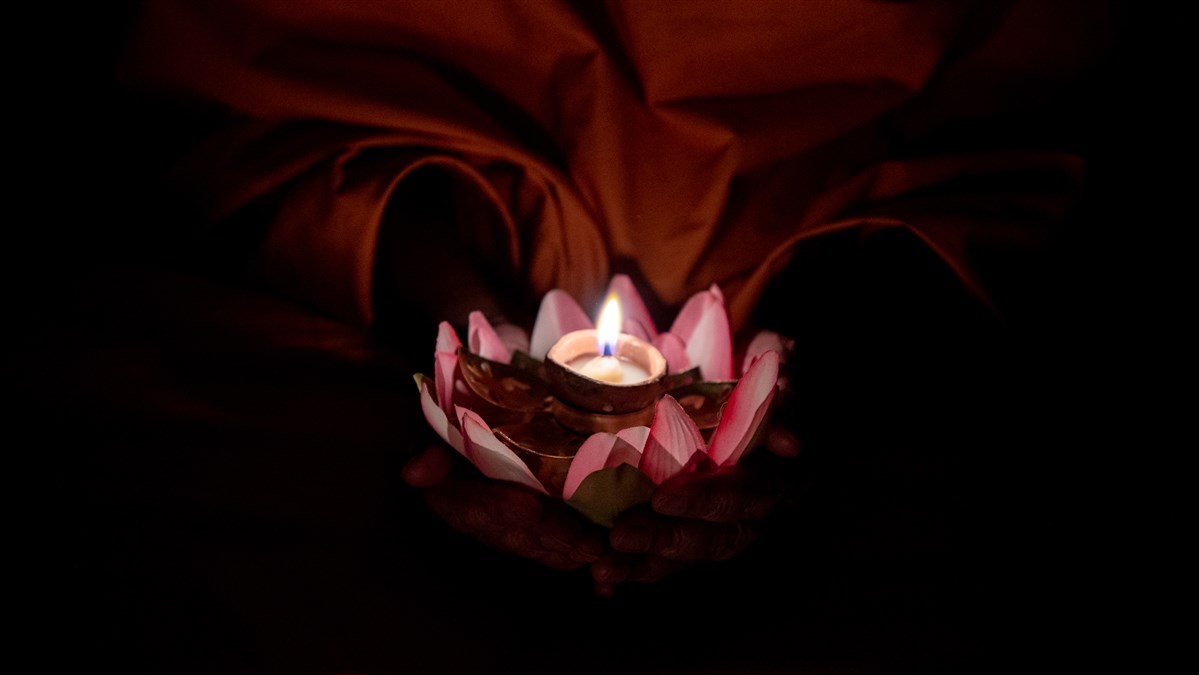 Swamishri holds a lamp