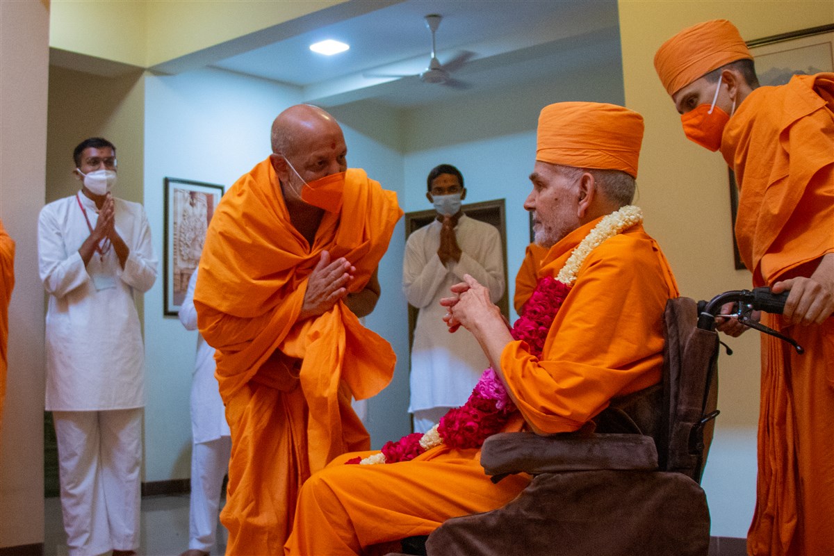 Dharmavatsal Swami honors Swamishri with a garland