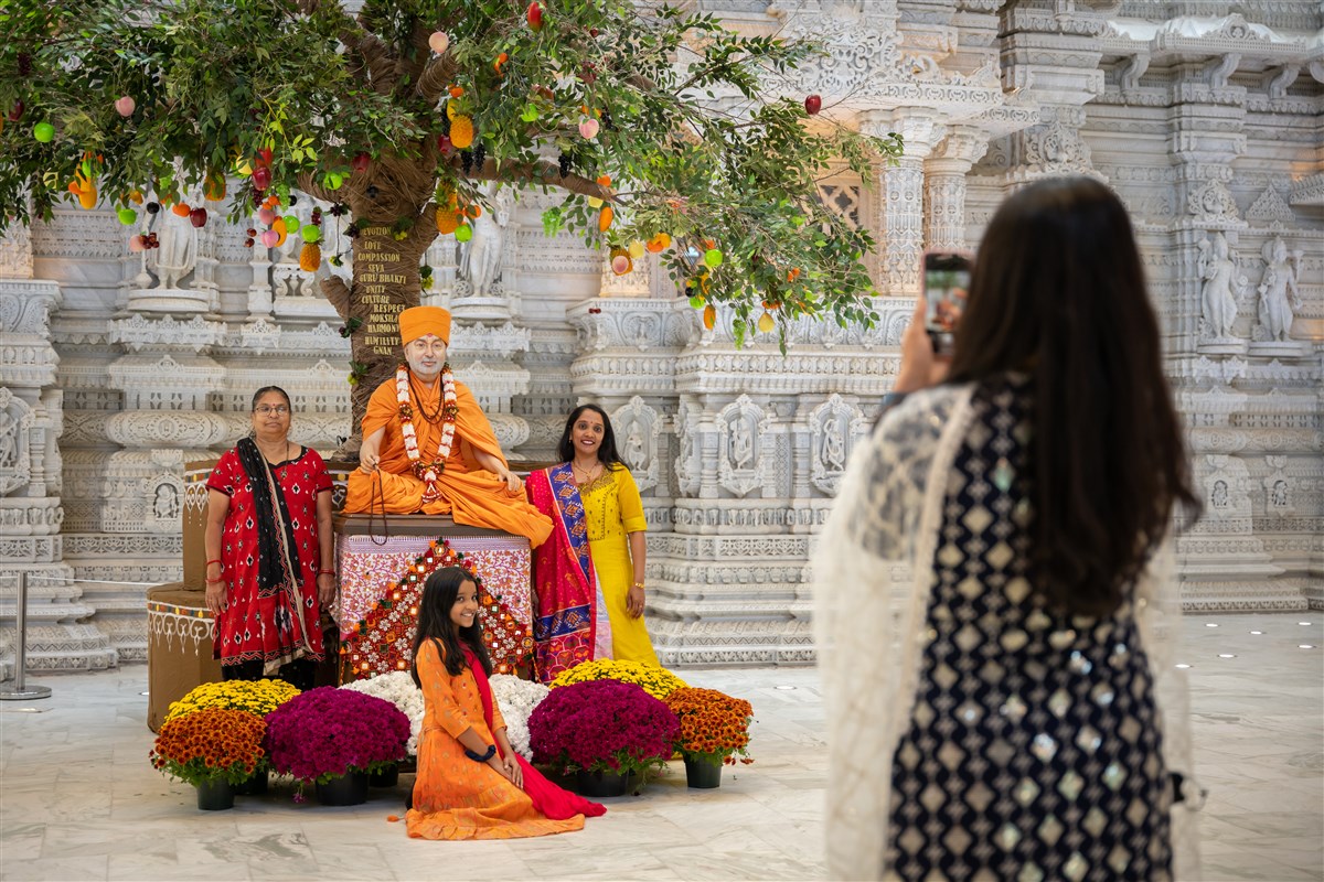 Three generations of women joyously gather for a photo with their guru, Pramukh Swami Maharaj.