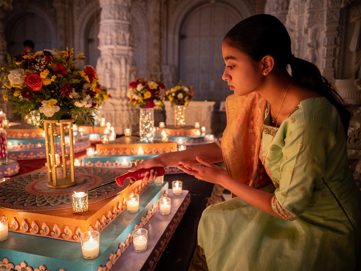 A youth volunteer introspects as she lights a candle marking the transition from darkness to light. This tradition is at the heart of Diwali celebrations.