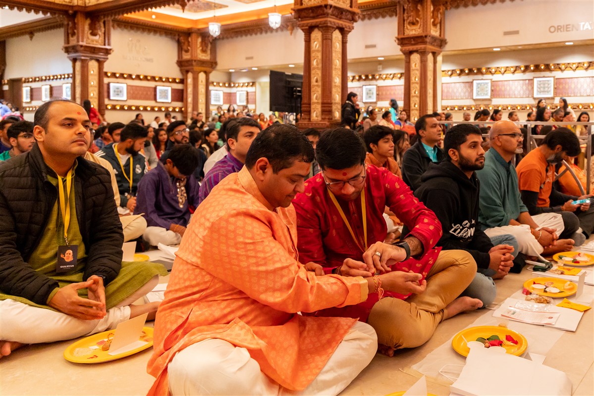 Devotees tie a sacred thread (nada chadi) on each other's wrists as they participate in the Chopda Pujan.