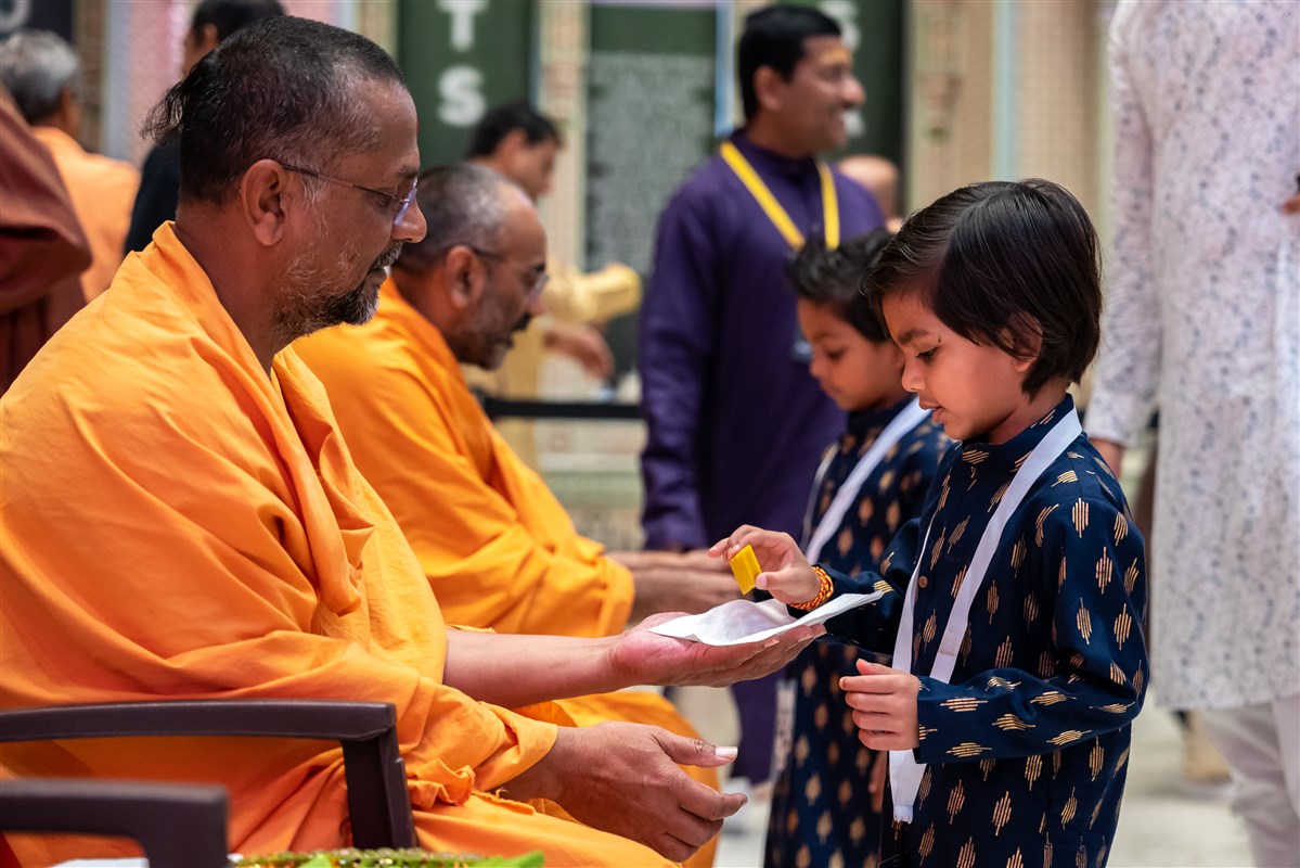 A Swami offers traditional sweets to a young child on the Hindu New Year day.
