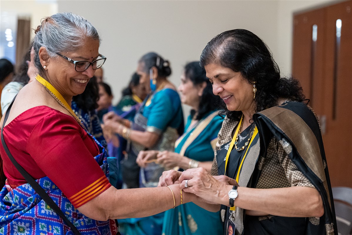 A volunteer ties a sacred thread around the wrist of her fellow volunteer on the Hindu New Year day.