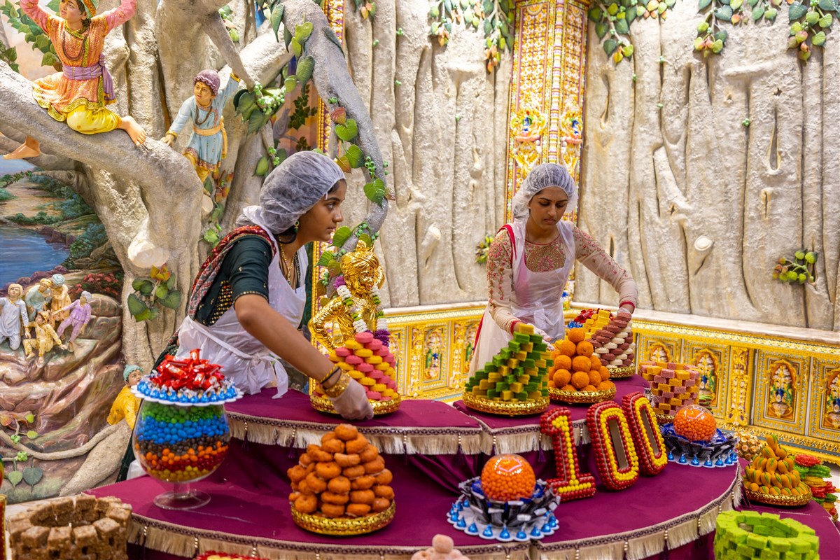 A youth volunteer helps arrange the Annakut, the ceremonial offering of food to the Deities