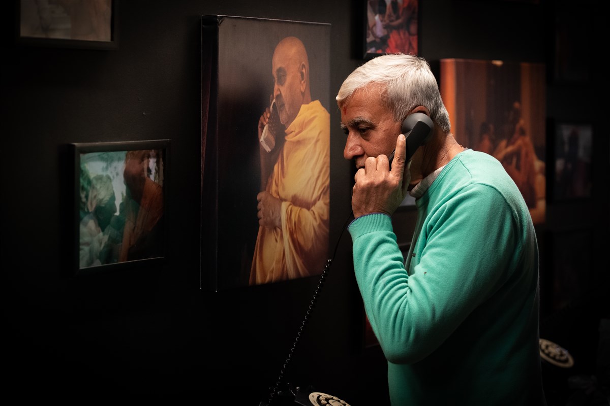 A visitor listens to a heartfelt telephone recording of Pramukh Swami Maharaj blessings a family.