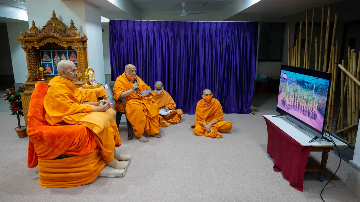Swamishri watches a video during the lunar eclipse assembly