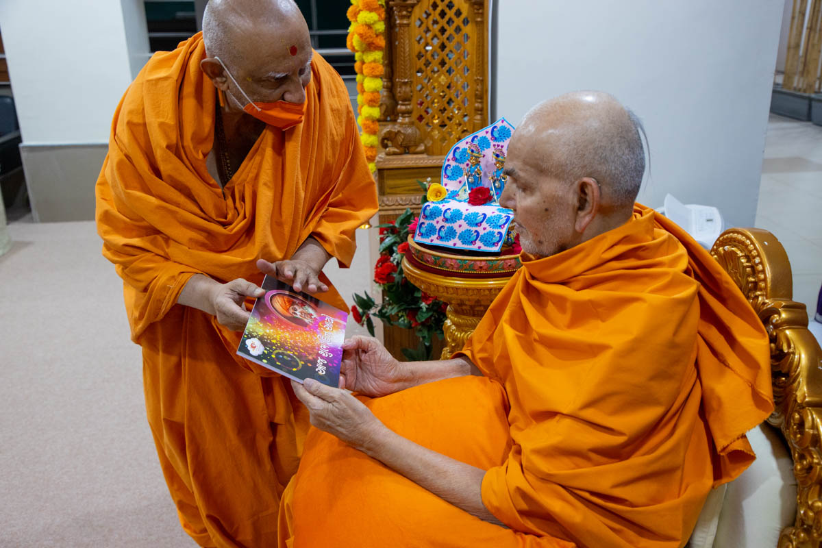 Swamishri observes the poster for a new audio publication