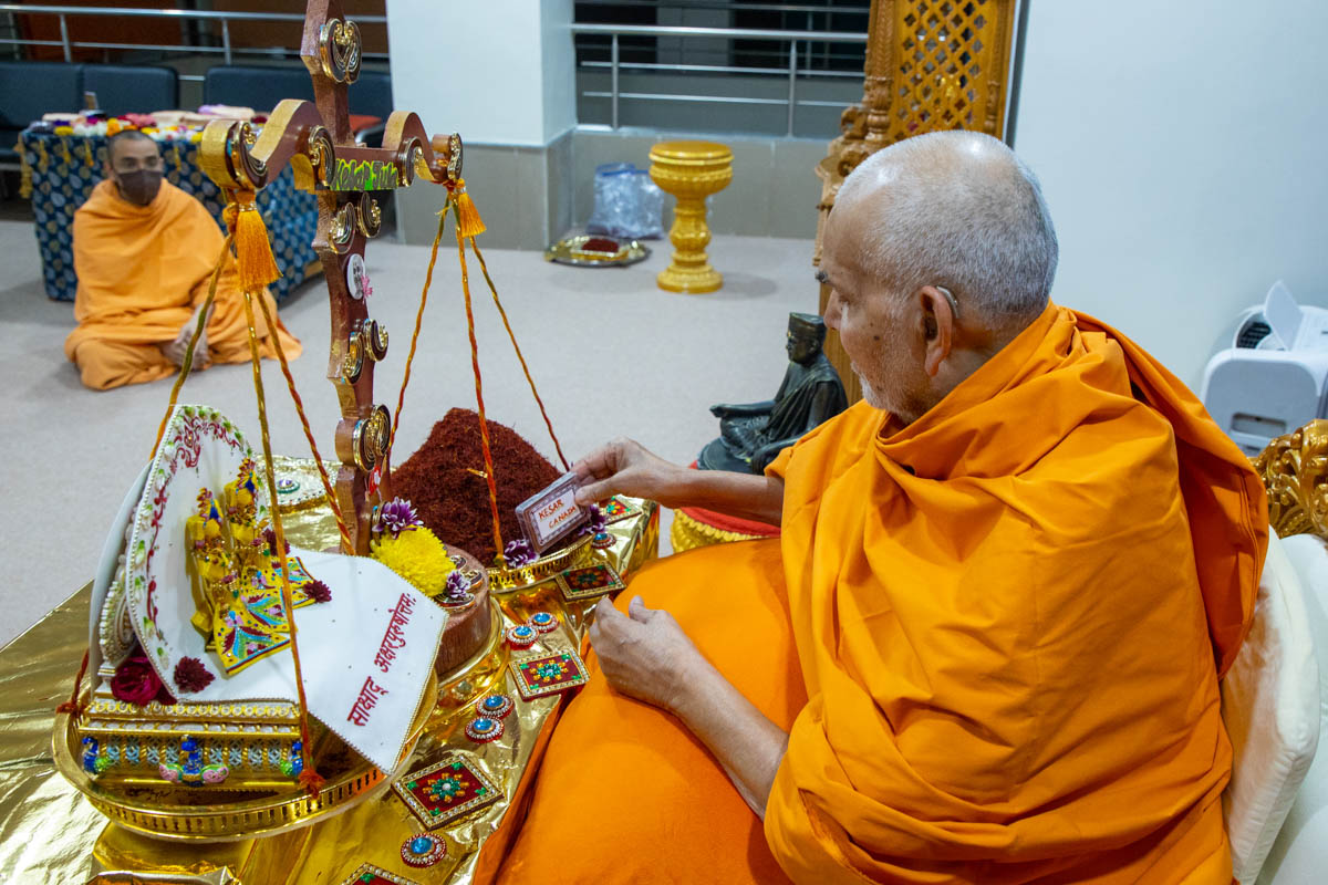 Swamishri performs the tula rituals with saffron