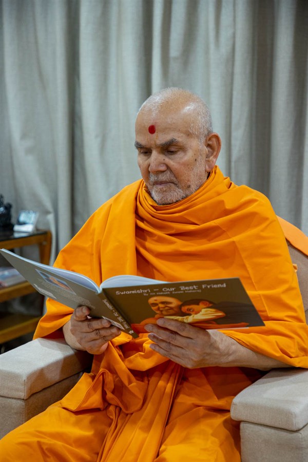 Swamishri reads a book 'Swamishri - Our Best Friend'