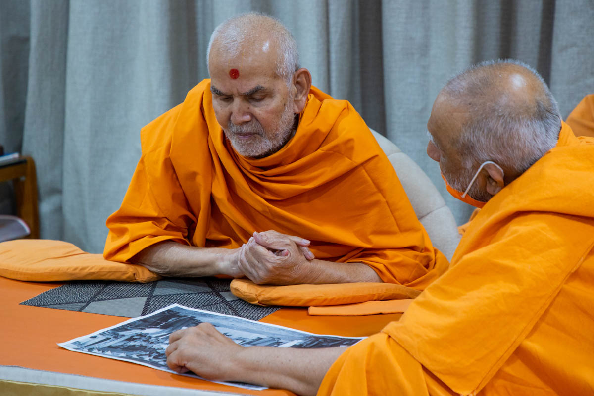 Swamishri observes an old photo of Brahmaswarup Yogiji Maharaj