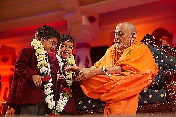 Swamishri garlands two young schoolchildren