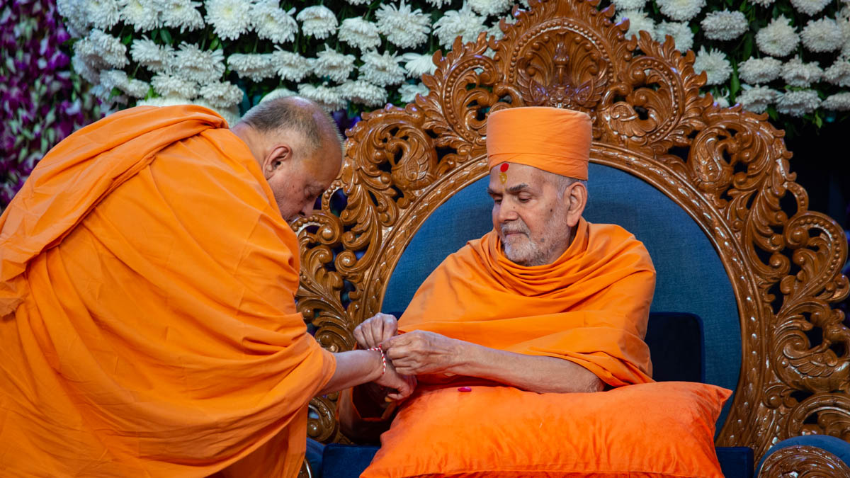 Swamishri ties a nadachhadi to Pujya Ishwarcharan Swami