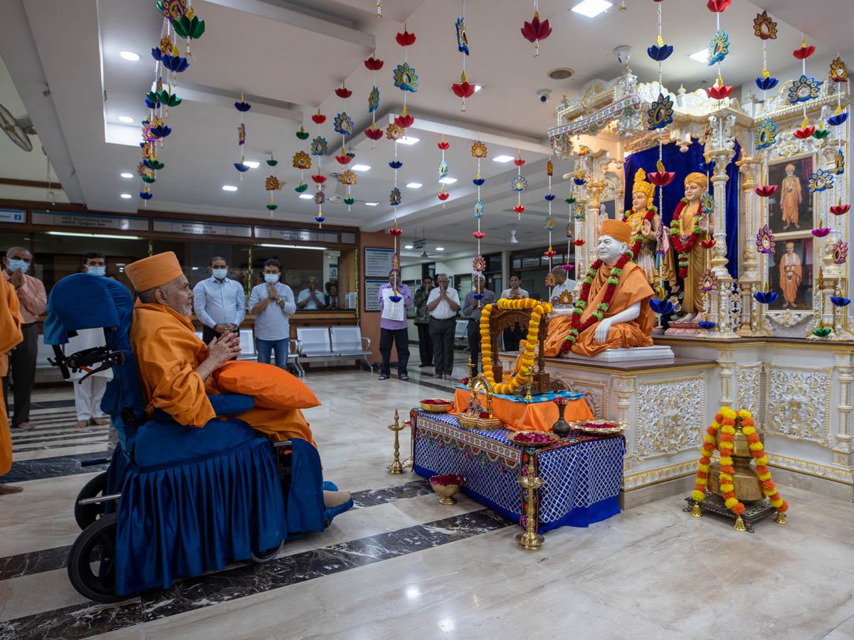 Swamishri engrossed in darshan of Shri Akshar-Purushottam Maharaj and Brahmaswarup Yogiji Maharaj at BAPS Yogiji Maharaj Hospital, Ahmedabad