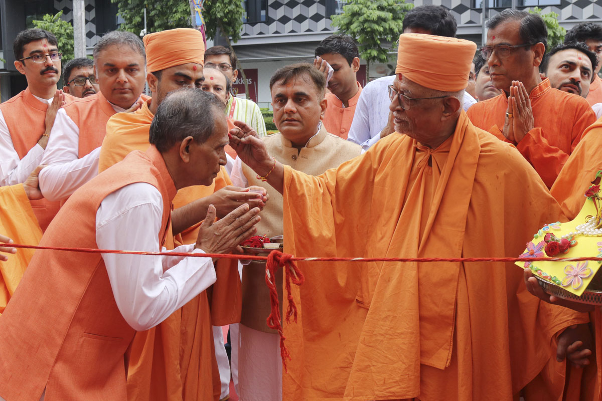 Pujya Doctor Swami applies a chandlo to a devotee