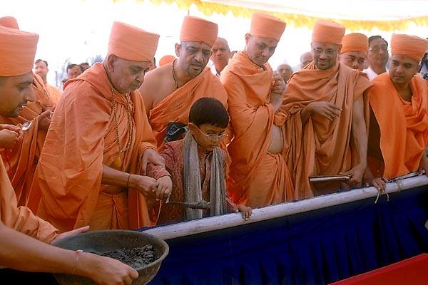 Swamishri pours cement into the foundation pit  	 