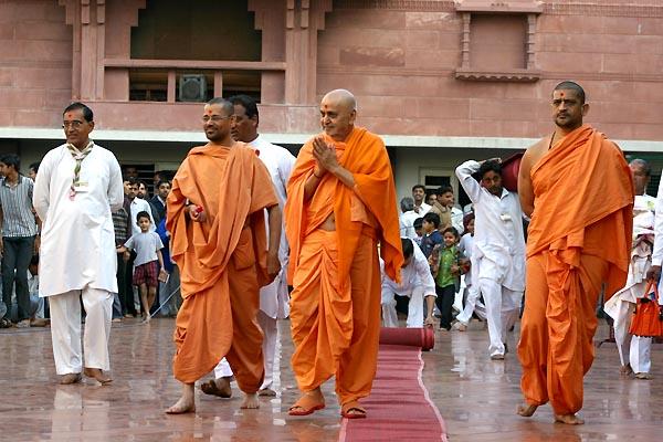 After his morning puja, Swamishri humbly responds to the children and devotees while returning to his quarters