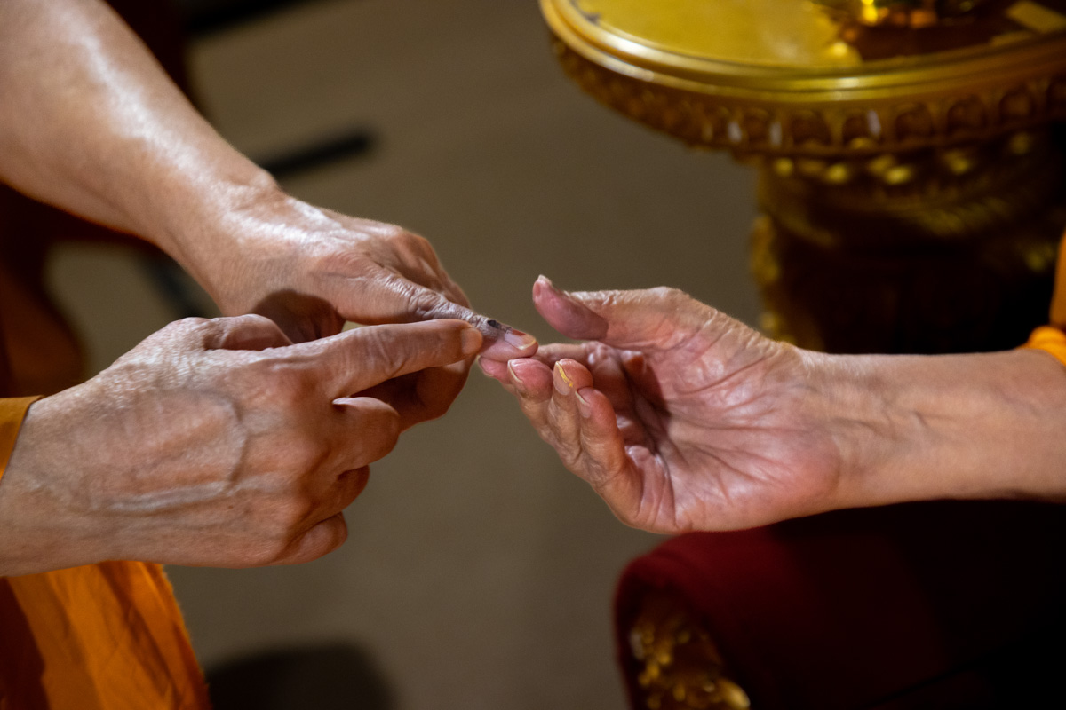 Swamishri observes the voting mark on Pujya Ishwarcharan Swami's finger