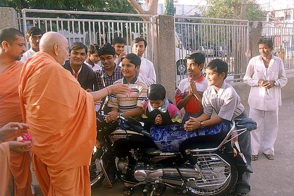 While performing pujan of a motorcycle Swamishri talks to children