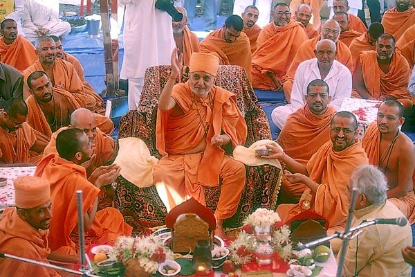 Swamishri blesses all by showering rice grains