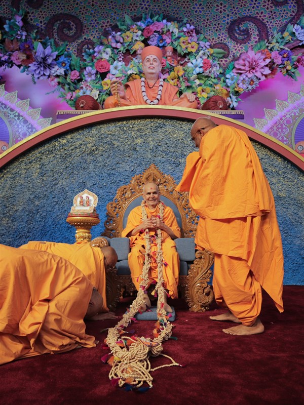 Nikhilesh Swami and sadhus honor Swamishri with a garland