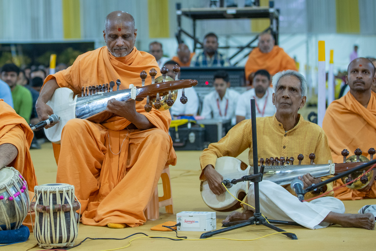 A sadhu and a well-wisher play the sarod in Swamishri's daily puja