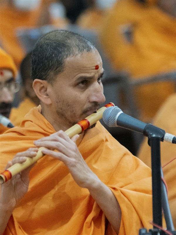 A sadhu plays the flute in Swamishri's daily puja