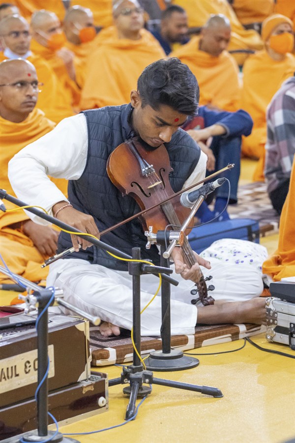 A youth plays the violin in Swamishri's daily puja