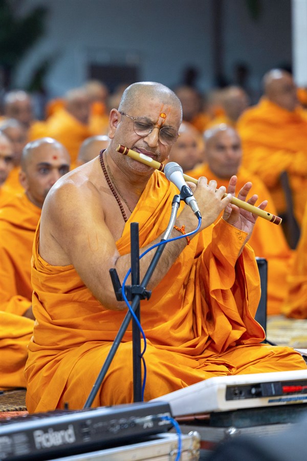 Rahul Swami plays the flute in Swamishri's daily puja