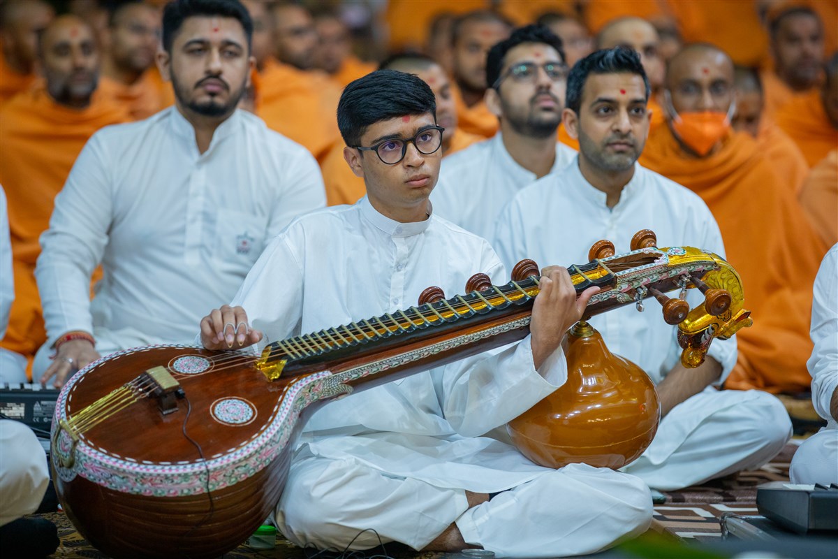 A youth plays the veena in Swamishri's daily puja