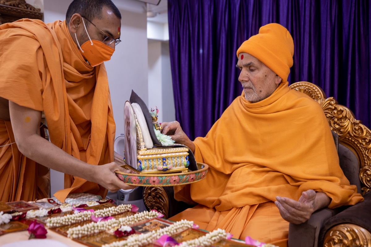 Swamishri offers a flower to Shri Harikrishna Maharaj and Shri Gunatitanand Swami