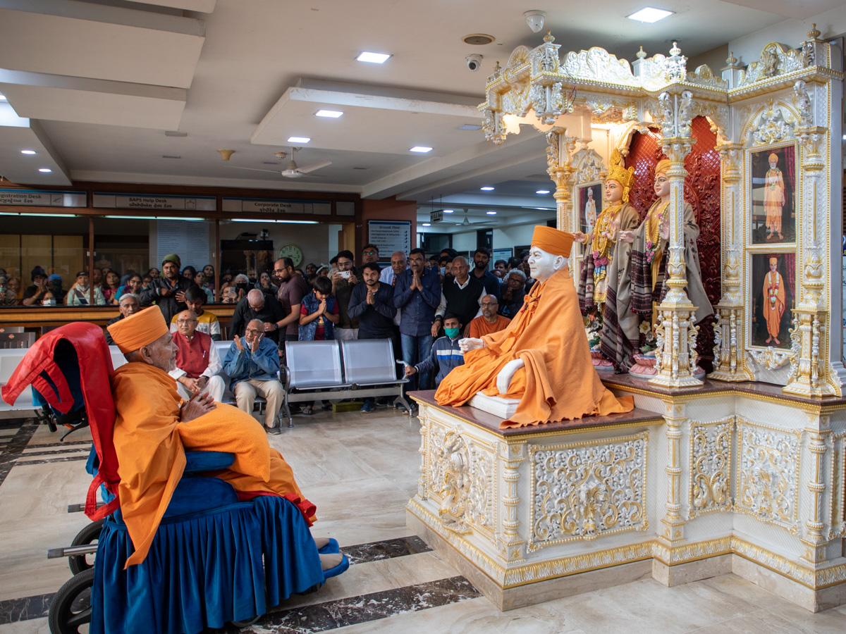 Swamishri engrossed in darshan of Shri Akshar-Purushottam Maharaj and Brahmaswarup Yogiji Maharaj at BAPS Yogiji Maharaj Hospital, Ahmedabad