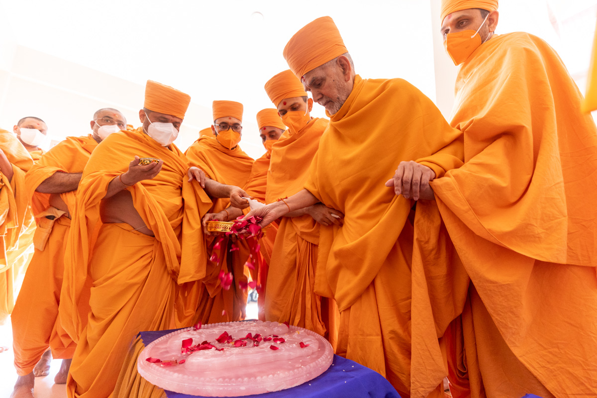 Swamishri offers flowers on the charanarvind of Bhagwan Swaminarayan
