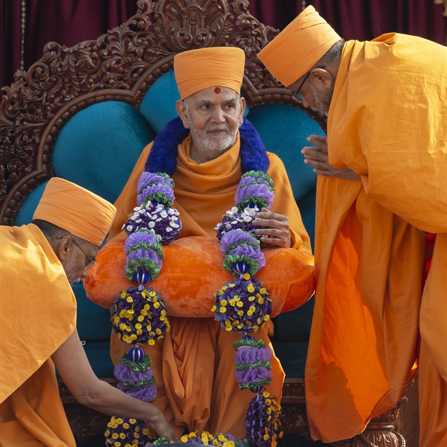 Gnaneshwar Swami and Narayanmuni Swami honor Swamishri with a garland