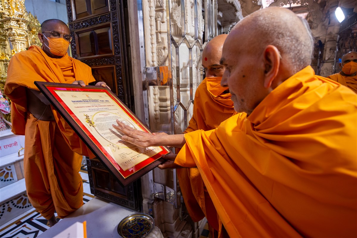 Swamishri sanctifies a certificate presented to Gnanvatsal Swami